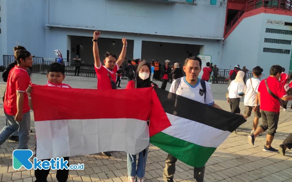 Thumbnail Andi Iswoyo bersama kedua anaknya mendukung timnas Indonesia dan Palestina dengan membawa bendera kedua negara, Rabu (14/6/2023). (Foto : M.Khaesar/Ketik.co.id)